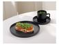 Une tasse noire avec du thé à la menthe, une assiette noire avec un toast et une soucoupe noire