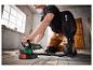 Un homme ponce un parquet en bois avec une ponceuse Parkside.