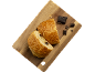 Deux pains au chocolat coupés sur une planche en bois avec des morceaux de chocolat.