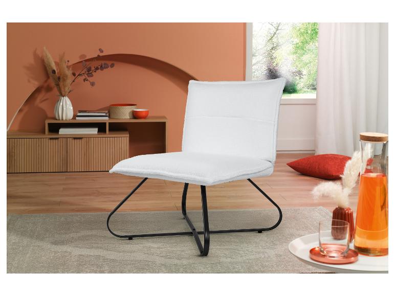 Un fauteuil blanc moelleux avec une structure en métal noir se trouve dans un salon moderne.