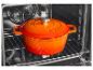 Cocotte en fonte émaillée orange avec couvercle dans un four.