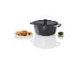 Une casserole noire avec un couvercle et des légumes grillés dans une assiette.