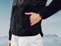 Veste en polaire noire et pantalon blanc devant des montagnes.