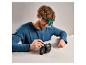 Homme répare un appareil photo avec une loupe et des outils.