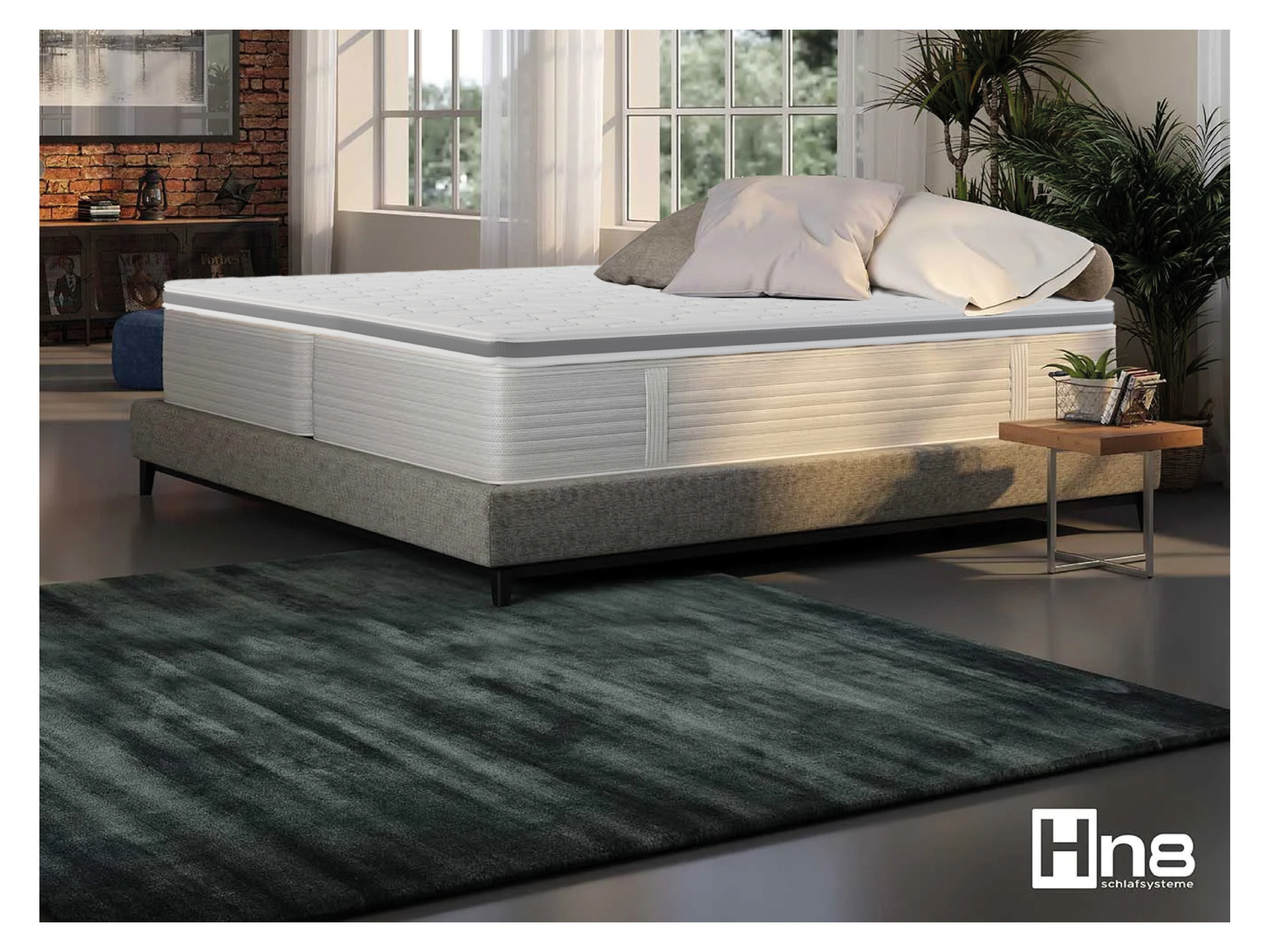 Un matelas et un sommier Hn8 Schlafsysteme dans une chambre avec un tapis vert foncé.