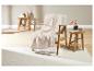 Une couverture en laine beige sur une chaise en bois dans une pièce claire.