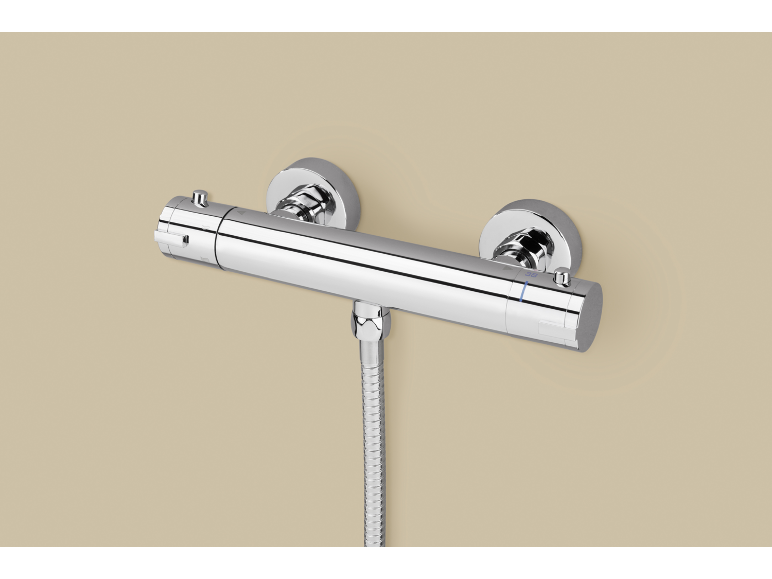 Mitigeur de douche thermostatique chromé avec flexible sur un mur beige.