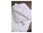 Couette ou couverture matelassée blanche pliée sur une surface marron