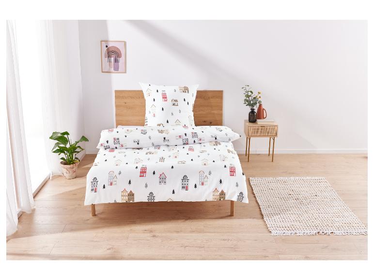 Parure de lit avec un motif de petites maisons sur fond blanc.