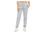 Une femme porte un pantalon de survêtement gris avec un logo et des baskets blanches.