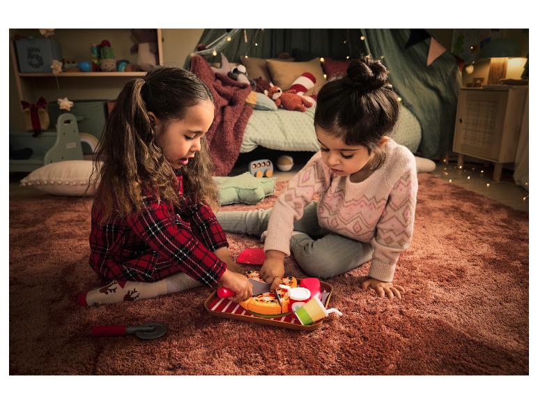 Deux petites filles jouent avec une pizza en plastique et un couteau à pizza.