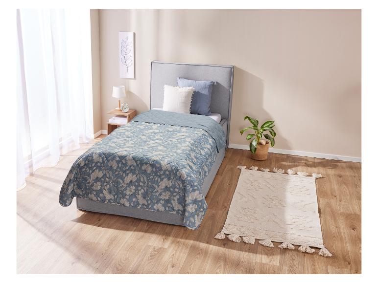 Couverture matelassée fleurie et tapis bohème dans une chambre à coucher.