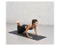 Une femme en tenue de sport fait des pompes sur un tapis de yoga noir à imprimé léopard.