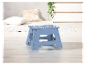 Tabouret pliable bleu clair à pois blancs sur un sol en bois.