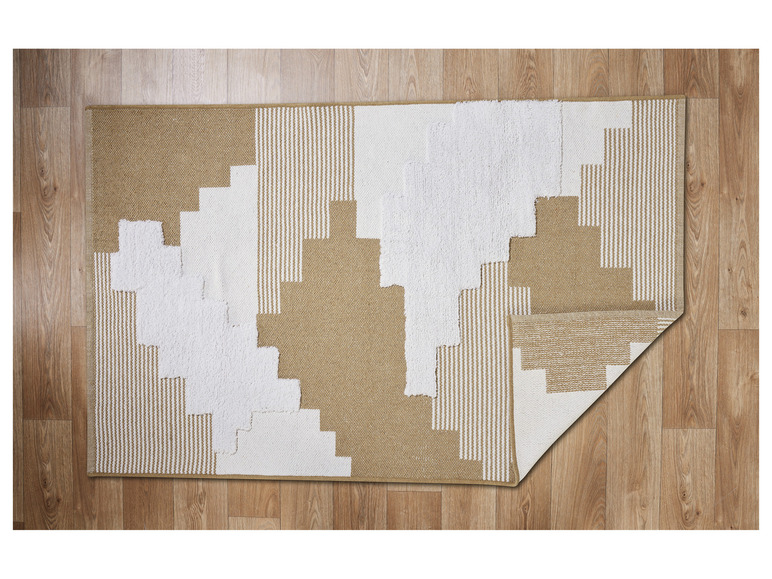 Un tapis beige et blanc avec un motif géométrique sur un sol en bois.