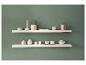 Deux étagères flottantes blanches sur un mur vert, ornées de divers objets décoratifs et céramiques.