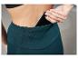 Une femme porte un legging de sport vert foncé avec un téléphone dans la poche.