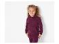 Une fille porte un sweat à capuche et un pantalon de survêtement bordeaux.