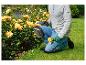 Un homme agenouillé dans le jardin avec des genouillères et des sécateurs.