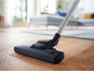 Une tête d'aspirateur Philips avec une brosse sur un sol en bois.