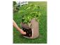 Une personne plante des pommes de terre dans un sac de culture sur l'herbe.