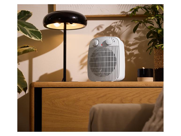 Un radiateur blanc et une lampe de table noire sur un meuble en bois.