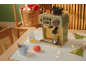 Machine à café jouet avec accessoires, une tasse de chocolat chaud et des décorations de Noël.