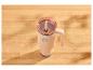 Mug isotherme beige avec anse et couvercle transparent sur une table en bois.