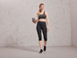 Une femme en tenue de sport tenant un ballon de fitness gris de la marque Grit.