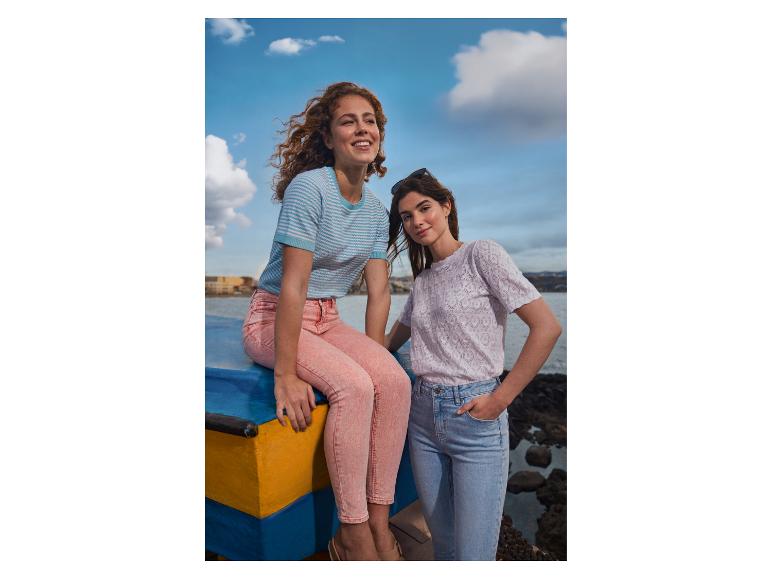 Deux femmes en t-shirts et jeans, l'une assise sur un bateau, l'autre debout.