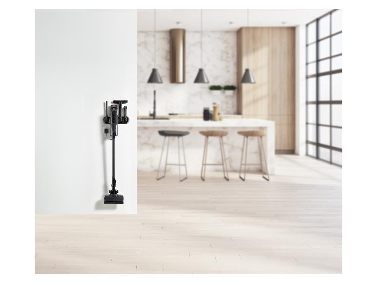 Aspirateur balai et accessoires accrochés au mur dans une cuisine moderne.