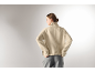 Femme en pull à col roulé beige et pantalon gris, vue de dos