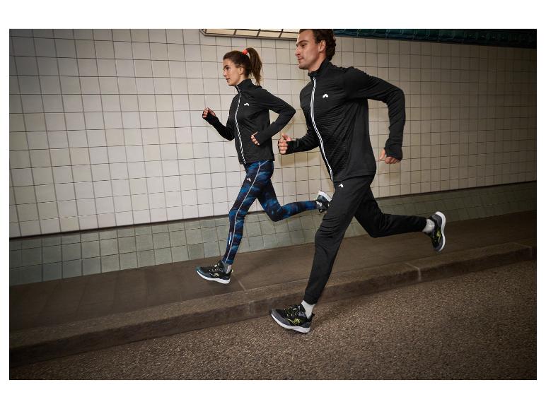Deux coureurs en vestes et pantalons de course noirs avec des détails blancs et bleus dans un tunnel.