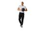 Homme portant jogging noir et t-shirt blanc, tenant un ballon de médecine.