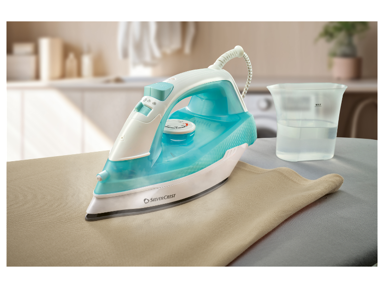 Un fer à repasser à vapeur Silvercrest repasse un tissu beige sur une planche à repasser.