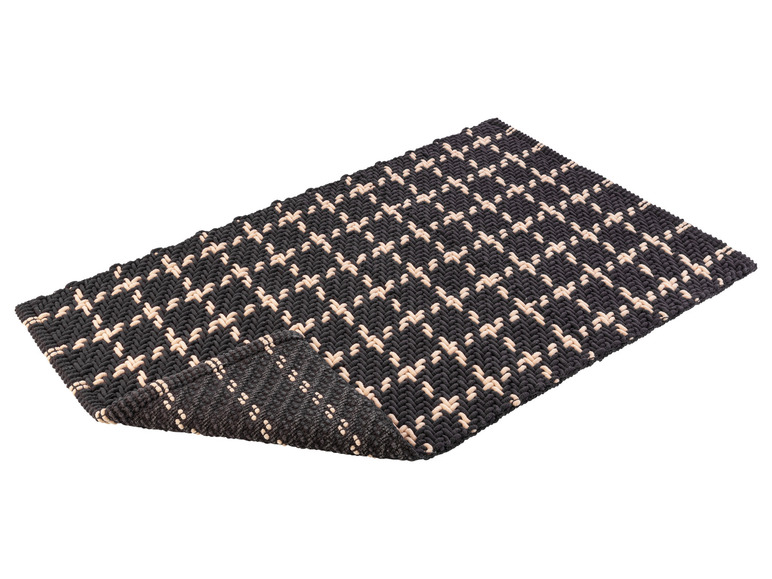 Un paillasson tissé noir et blanc avec un motif géométrique.