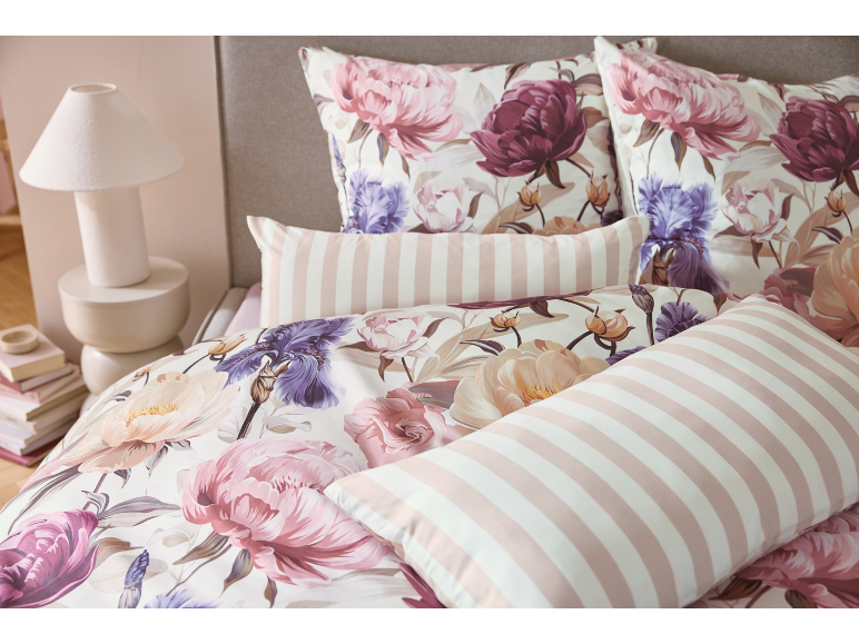 Parure de lit florale avec pivoines et iris, avec oreillers rayés roses et blancs.