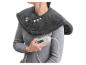 Femme portant un chauffe-épaules et cou gris, tenant une télécommande.