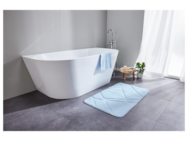 Une baignoire blanche avec un tapis de bain bleu dans une salle de bain moderne.