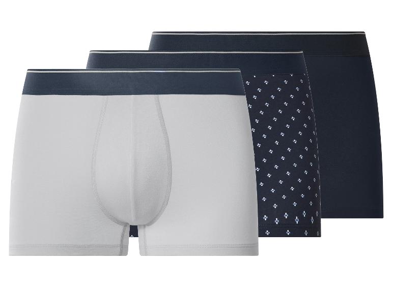 Trois boxers pour hommes : un gris clair, un bleu foncé à motifs et un bleu foncé uni.