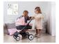 Deux enfants jouent avec une poussette rose Maxi-Cosi.