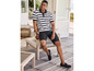 Un homme en polo rayé, short et mocassins sur une terrasse.