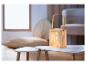 Une lampe en bois avec un motif tressé sur une table blanche.
