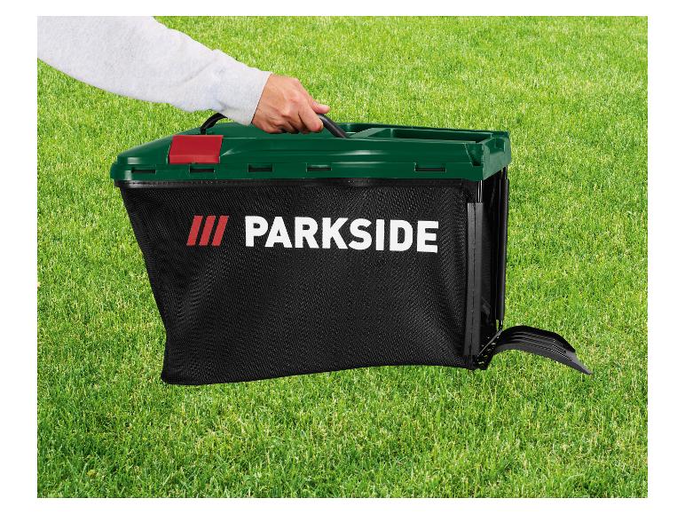 Main tenant un sac de ramassage d'herbe Parkside noir avec un couvercle vert foncé sur de l'herbe verte.