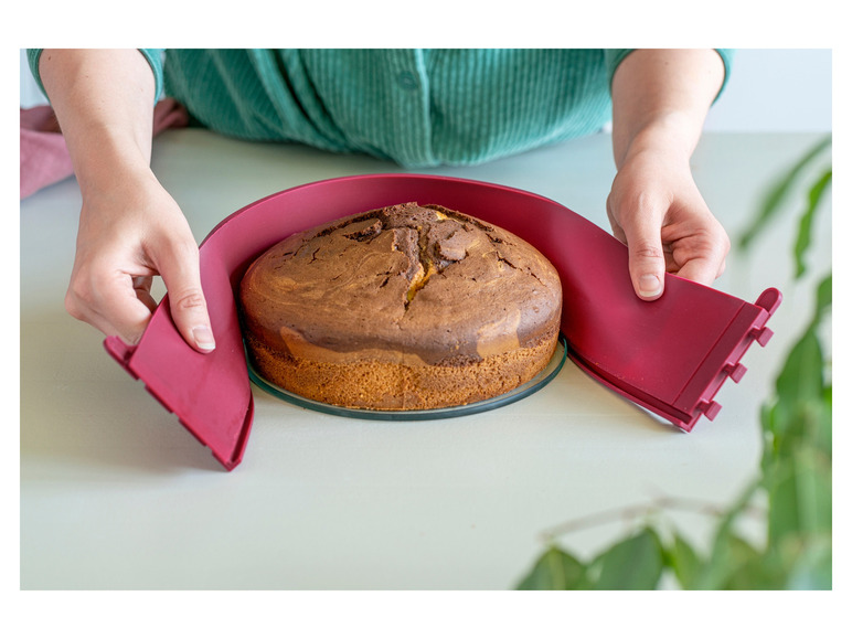 Un gâteau marbré sur un plateau à gâteau en verre, entouré d'un moule à gâteau en silicone rose.