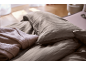 Gros plan d'un lit avec une parure de lit marron rayée et une couverture rose clair.