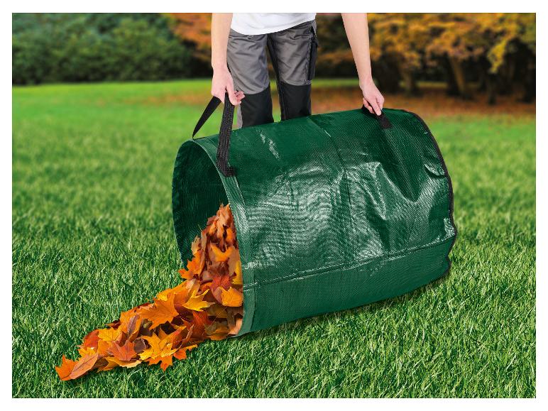 Personne vidant un sac de déchets de jardin vert rempli de feuilles d'automne sur l'herbe.