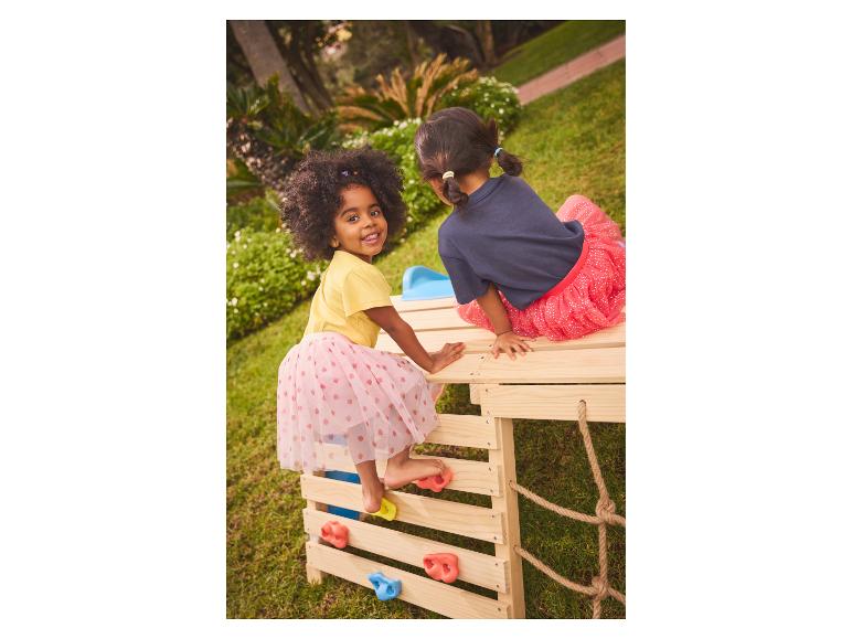 Deux filles jouent sur une structure d'escalade en bois dans le jardin.