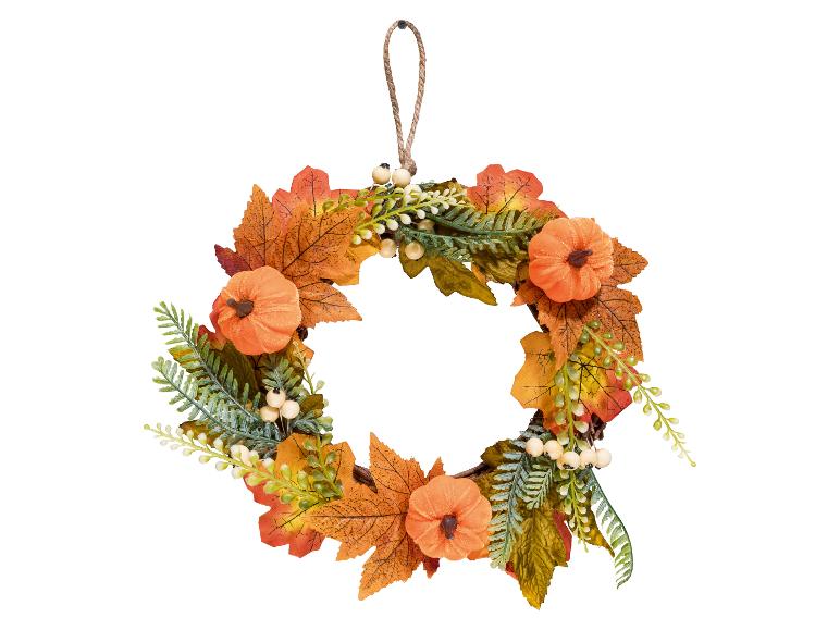 Couronne d'automne avec des feuilles oranges, de petites citrouilles et des baies
