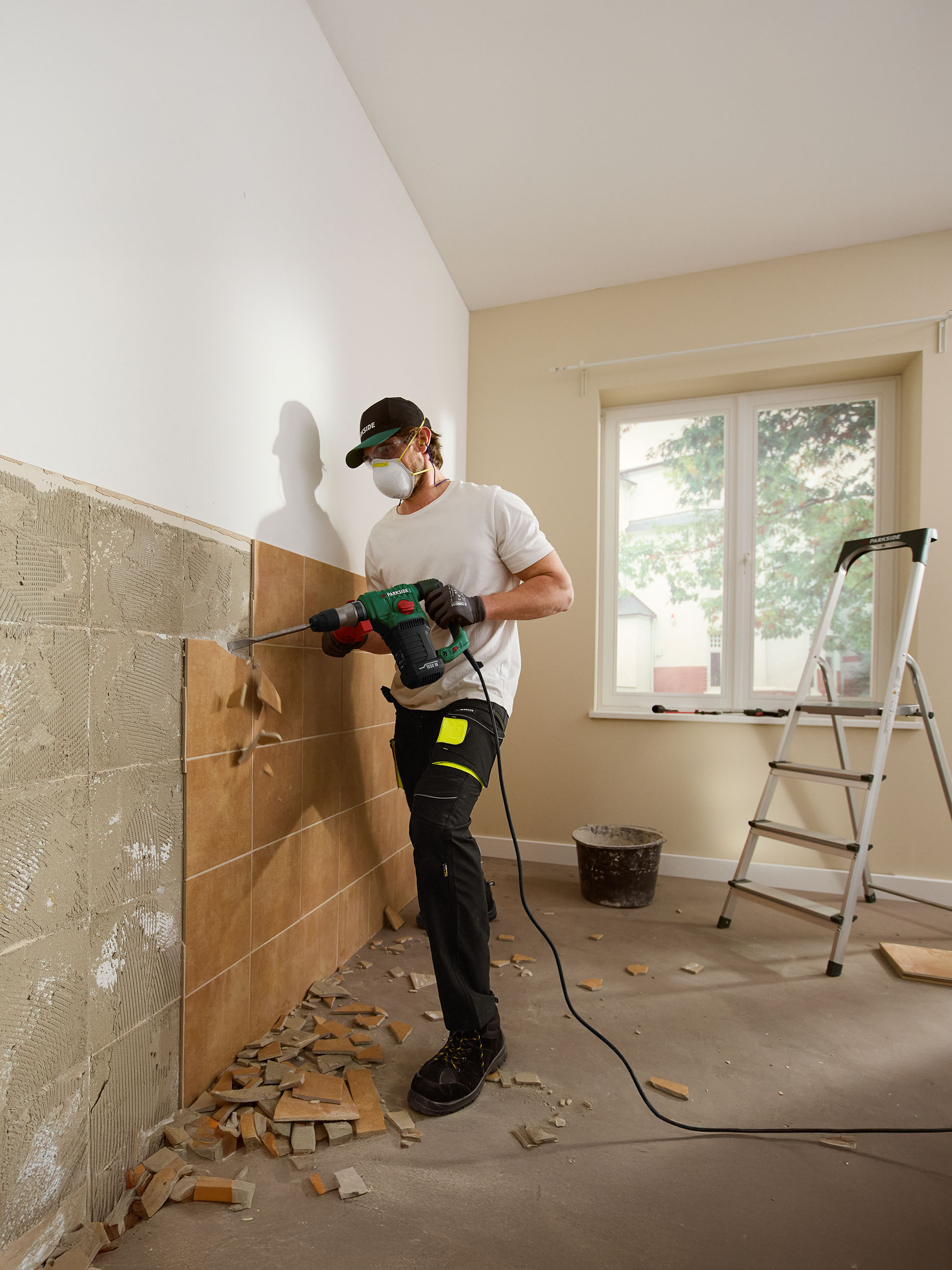 Homme retirant des carreaux d'un mur avec un marteau perforateur Parkside.